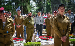 People stand still as a two-minute siren sounded across Israel, marking Memorial Day at Mount Herzl Military Cemetery in Jerusalem on April 30, 2025. (Arie Leib Abrams/Flash90)