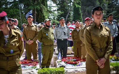 People stand still as a two-minute siren sounded across Israel, marking Memorial Day at Mount Herzl Military Cemetery in Jerusalem on April 30, 2025. (Arie Leib Abrams/Flash90)
