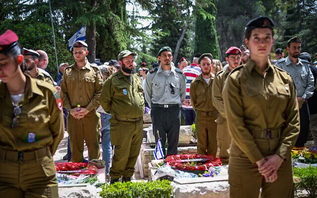 People stand still as a two-minute siren sounded across Israel, marking Memorial Day at Mount Herzl Military Cemetery in Jerusalem on April 30, 2025. (Arie Leib Abrams/Flash90)