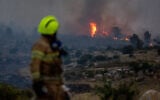 A firefighter looks on as a wildfire rages near Mevo Horon, near Modi'in, April 30, 2025. (Yonatan Sindel/Flash90)