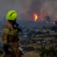 A firefighter looks on as a wildfire rages near Mevo Horon, near Modi'in, April 30, 2025. (Yonatan Sindel/Flash90)