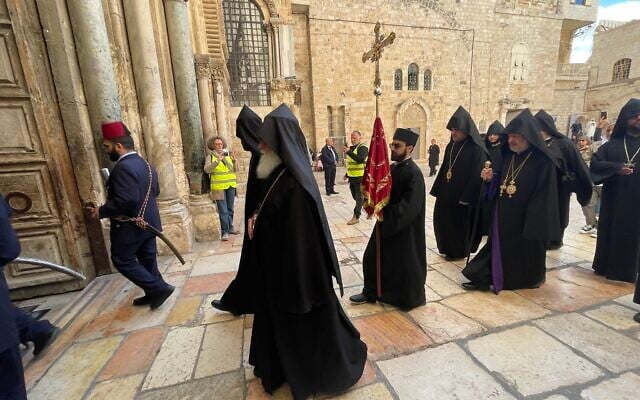 Armenian Christians, accompanied by Israeli volunteers, enter the Church of the Holy Sepulcher on Palm Sunday, April 13, 2025. (Sue Surkes/Times of Israel)