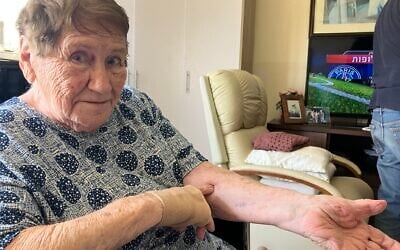 Holocaust survivor Chana Sandouvsky shows her A-14147 number tattoo from Auschwitz in her home in Kiryat Bialik on April 16, 2025. (Diana Bletter/Times of Israel)