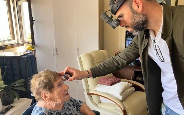 Dr. Yosif Boulos, right, a volunteer eye doctor with  LeMa’anam (“for their sake” in Hebrew), a non-profit organization providing timely healthcare free of charge to Holocaust survivors in their homes, examines the eyes of Chana Sandouvsky in her home in Kiryat Bialik on April 16, 2025. (Diana Bletter/Times of Israel)