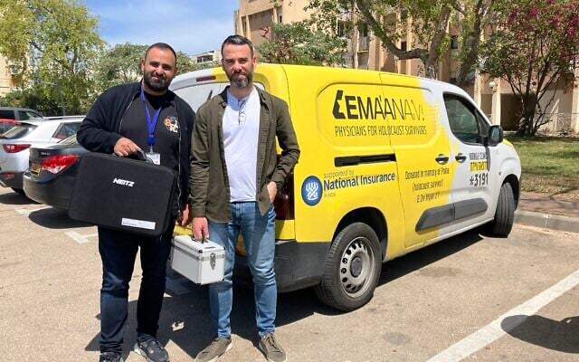 Dr. Fadi Badarna, left, and Dr. Yosif Boulos, volunteer eye doctors with  LeMa’anam (“for their sake” in Hebrew), a non-profit organization providing timely healthcare free of charge to Holocaust survivors in their homes, by a LeMa'anam van as they stop to make a house call in Kiryat Yam on April 16, 2025. (Diana Bletter/Times of Israel)
