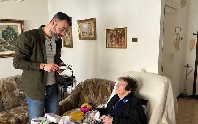 Dr. Yosif Boulos, a volunteer eye doctor with LeMa’anam (“for their sake” in Hebrew), a non-profit organization providing timely healthcare free of charge to Holocaust survivors in their homes, talks to Henia Hirsh during her eye examination at her home in Kiryat Yam on April 16, 2025. (Diana Bletter/Times of Israel)