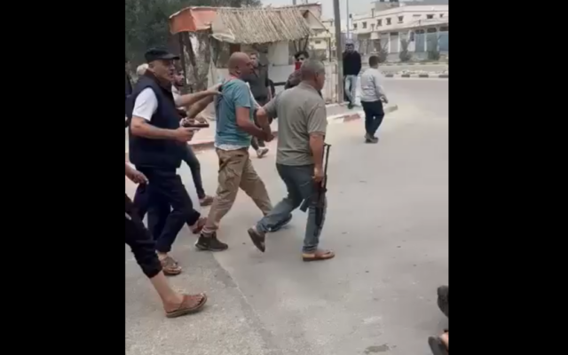 Screenshot of a social media video showing armed members of the Abu Samra family taking an alleged Hamas member by the arm, who they later executed for killing a a member of their family, Deir al-Balah, Gaza Strip, April 1, 2025. (Screenshot from X, used in accordance with Clause 27a of the Copyright Law) Screenshot of a social media video showing armed members of the Abu Samra family taking an alleged Hamas member by the arm, who they later executed for killing a a member of their family, Deir al-Balah, Gaza Strip, April 1, 2025. (Screenshot from X, used in accordance with Clause 27a of the Copyright Law)