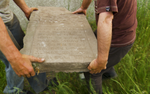 A Jewish tombstone being moved in Gniewoszów, Poland, an element in 'Among Neighbors,' filmmaker Yoav Potash's documentary about a Polish town, screened in Israel for Holocaust Remembrance Day, starting April 23, 2025 (Courtesy)