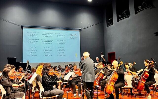 Conductor Michael Wolpe, with released hostage Agam Berger, center, performing with the Lu Yehi Orchestra in Jerusalem on April 8, 2025 (Courtesy)
