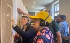Holocaust survivor Suzanne Rosenberg, far left, looks in the Book of Names at Block 27 at Auschwitz to find her uncle's name on April 23, 2025 (Jessica Steinberg/Times of Israel)