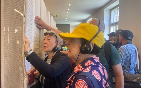 Holocaust survivor Suzanne Rosenberg, far left, looks in the Book of Names at Block 27 at Auschwitz to find her uncle's name on April 23, 2025 (Jessica Steinberg/Times of Israel)