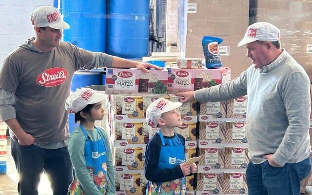 Streit's co-owners Aaron Gross, far left, and Aron Yagoda, far right, give two young visitors a tour of the matzah factory. (Courtesy Streit's via JTA)