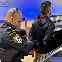 An Israel Police officer, left, arrests a West Bank Palestinian man who spat on an IDF soldier in central Israel and later turned himself in, on May 18, 2025. (Israel Police)
