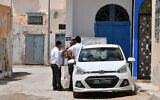 Illustrative: Tunisian Jews stand next to a car in the Hara Kebira, the main Jewish quarter in the resort island of Djerba, after attending a ceremony at the Ghriba synagogue following a shooting spree by a police officer on the southern Tunisian island on May 10, 2023. (FETHI BELAID / AFP)