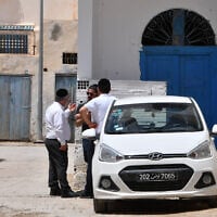 Illustrative: Tunisian Jews stand next to a car in the Hara Kebira, the main Jewish quarter in the resort island of Djerba, after attending a ceremony at the Ghriba synagogue following a shooting spree by a police officer on the southern Tunisian island on May 10, 2023. (FETHI BELAID / AFP)