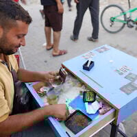 A man rolls and sells cigarettes on a street in Khan Younis, on the southern Gaza Strip on August 15, 2024. (Bashar TALEB / AFP)