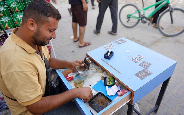 A man rolls and sells cigarettes on a street in Khan Younis, on the southern Gaza Strip on August 15, 2024. (Bashar TALEB / AFP)