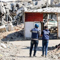 Journalists film while standing before destroyed buildings in the Jabalia camp for Palestinian refugees in the northern Gaza Strip on October 9, 2024. (Omar Al-Qattaa / AFP)