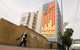 Women walk near a building bearing an anti-US mural with the slogan "Down with the USA" and skulls replacing the stars on the US flag, on Tehran's Karim Khan Zand avenue on April 26, 2025. (ATTA KENARE / AFP)
