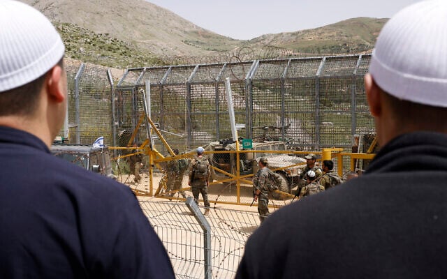 Israeli soldiers stand guard as Druze men demonstrate in solidarity with the Syrian Druze community, near the border barrier in the village of Majdal Shams in the Golan Heights on April 30, 2025. (Jalaa Marey/AFP) Israeli soldiers stand guard as Druze men demonstrate in solidarity with the Syrian Druze community, near the border barrier in the village of Majdal Shams in the Golan Heights on April 30, 2025. (Jalaa Marey/AFP)
