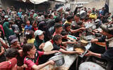 Palestinians gather to receive a hot meal at a food distribution center in the Nuseirat camp for refugees, in the central Gaza Strip, on April 30, 2025. (Eyad BABA / AFP)