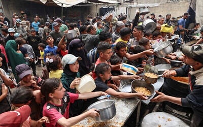 Palestinians gather to receive a hot meal at a food distribution center in the Nuseirat camp for refugees, in the central Gaza Strip, on April 30, 2025. (Eyad BABA / AFP)