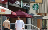 People walk past a Starbucks coffee shop in Riyadh, Saudi Arabia, on May 1, 2025. (Photo by Fayez Nureldine / AFP)