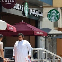 People walk past a Starbucks coffee shop in Riyadh, Saudi Arabia, on May 1, 2025. (Photo by Fayez Nureldine / AFP)