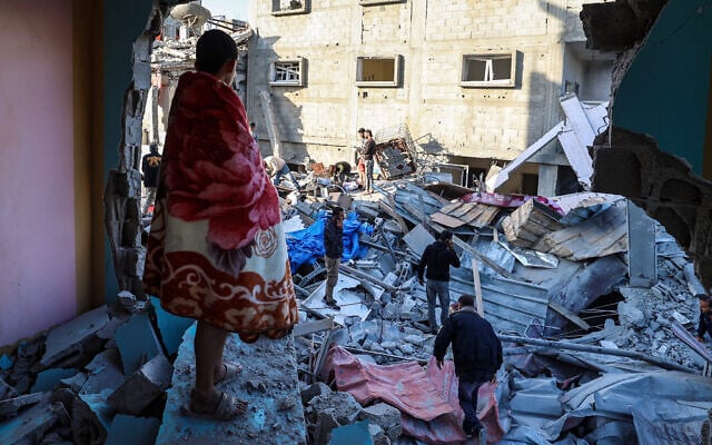 A youth draped in a blanket looks on as people look for survivors in the rubble of a building hit in an Israeli strike in the Bureij camp in the central Gaza Strip on May 2, 2025. (Photo by Eyad BABA / AFP)