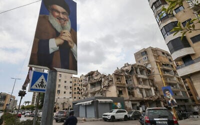 People drive on a street past portraits of slain Lebanese Hezbollah leader Hassan Nasrallah and buildings damaged in Israeli strikes in the recent war, amid the first round of municipal elections, in the Ghobeiry neighbourhood of Beirut's southern suburb on May 4, 2025. (ANWAR AMRO / AFP)