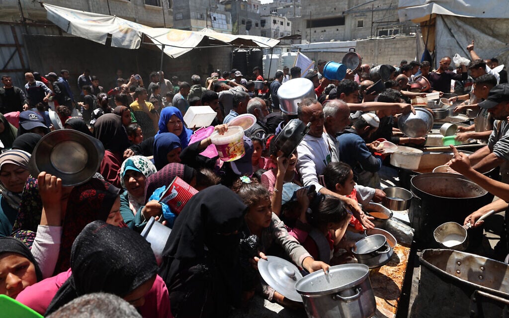 Palestinians queue for a hot meal at a charity kitchen at the Nuseirat refugee camp in the central Gaza Strip on May 4, 2025 (Eyad BABA / AFP)
