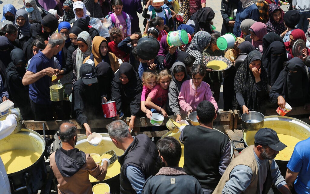 Displaced Palestinians queue for a portion of hot food at a charity kitchen at the Nuseirat refugee camp in the central Gaza Strip on May 5, 2025 (Eyad BABA / AFP)