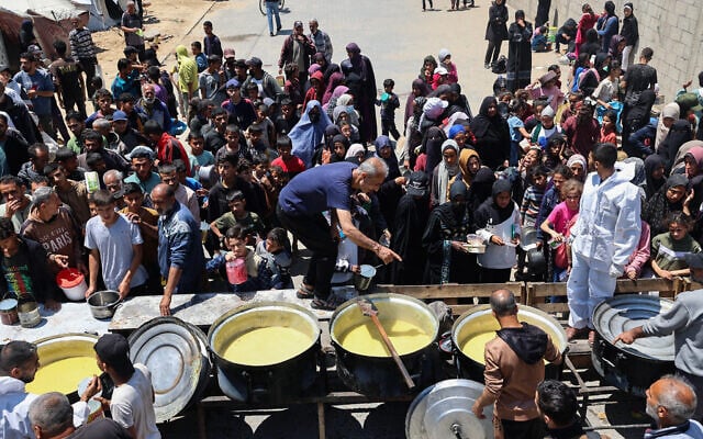 Displaced Palestinians line up for a portion of hot food at a charity kitchen at the Nuseirat refugee camp in the central Gaza Strip on May 5, 2025. (Eyad Baba/AFP)