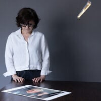 Iranian filmmaker and activist Sepideh Farsi looks at a portrait of the Palestinian photographer Fatima Hassouna, during a photo session at her home in Paris on May 5, 2025. (JOEL SAGET / AFP)
