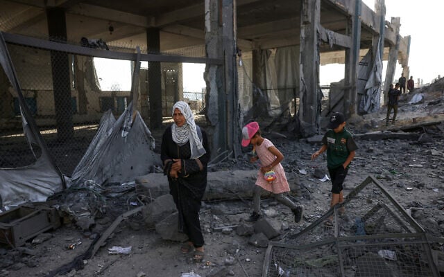 Displaced Palestinians walk amid the rubble of an UNRWA aid supply depot and shelter, heavily damaged in an overnight Israeli strike in Jabalia, in the northern Gaza Strip on May 10, 2025. (BASHAR TALEB / AFP)