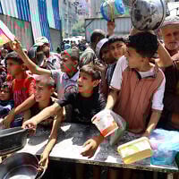 Palestinians jostle for position to get a hot meal, in front of a distribution point at the Nuseirat refugee camp in the central Gaza Strip on May 10, 2025. (Eyad BABA / AFP)