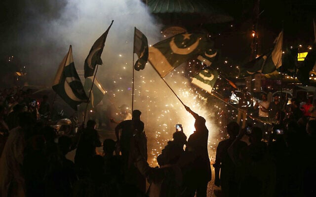 Pakistanis wave the national flag as they celebrate after the ceasefire between Pakistan and India, in Hyderabad, Sindh province, on May 10, 2025. (Photo by Husnain ALI / AFP)