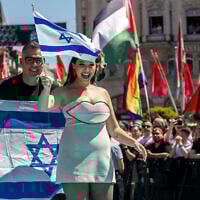 Israeli singer Yuval Raphael, representing Israel with the song, 'New Day Will Rise,' walks on the turquoise carpet next to the Basel Town Hall, with protesters' Palestinian flags behind, during the opening ceremony of the Eurovision Song Contest 2025  in Basel, Switzerland, on May 11, 2025. (Fabrice COFFRINI / AFP)