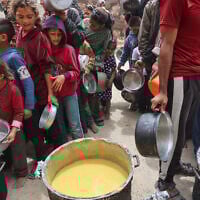 Palestinians line up to get a ration of hot food from a charity kitchen set up at the Islamic University campus in Gaza City on May 12, 2025. (Omar AL-QATTAA / AFP)