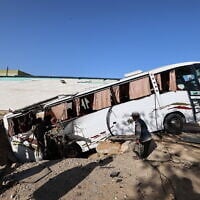 People check a bus inside a crater in the aftermath of an Israeli strike in Khan Younis in the southern Gaza Strip on May 14, 2025 (Eyad BABA / AFP)