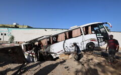 People check a bus inside a crater in the aftermath of an Israeli strike in Khan Younis in the southern Gaza Strip on May 14, 2025 (Eyad BABA / AFP)
