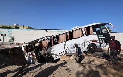 People check a bus inside a crater in the aftermath of an Israeli strike in Khan Younis in the southern Gaza Strip on May 14, 2025 (Eyad BABA / AFP)