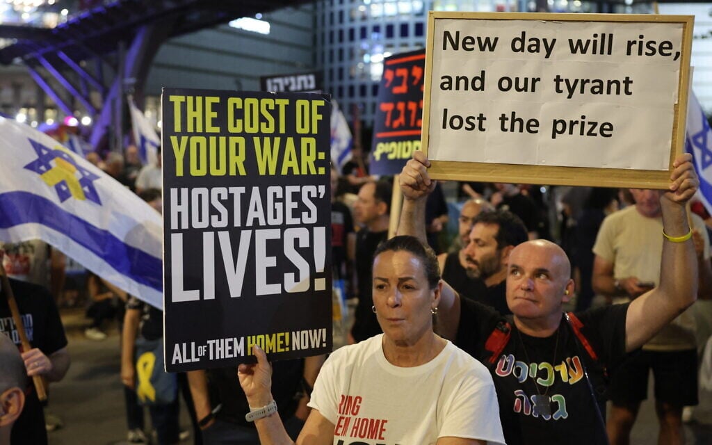 Demonstrators raise placards during an anti-government protest calling for the end of the war and for action to secure the release of hostages held by Palestinian terrorists in the Gaza Strip, in front of the Defense Ministry headquarters in Tel Aviv on May 17, 2025. (Photo by Jack GUEZ / AFP)