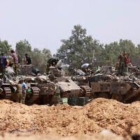 Israeli troops work on their armored vehicles at a position by the border with the Gaza Strip on May 18, 2025.  (Photo by Menahem KAHANA / AFP)