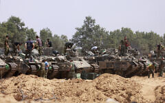 Israeli troops work on their armored vehicles at a position by the border with the Gaza Strip on May 18, 2025.  (Photo by Menahem KAHANA / AFP)