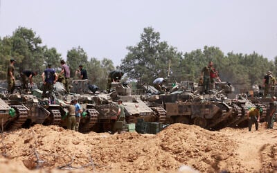 Israeli troops work on their armored vehicles at a position by the border with the Gaza Strip on May 18, 2025.  (Photo by Menahem KAHANA / AFP)