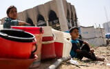 Children sit with plastic buckets as displaced Palestinians collect water in Gaza City, on May 20, 2025, amid the ongoing war between Israel and Hamas. (Bashar TALEB / AFP)