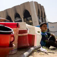 Children sit with plastic buckets as displaced Palestinians collect water in Gaza City, on May 20, 2025, amid the ongoing war between Israel and Hamas. (Bashar TALEB / AFP)