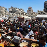Palestinians line up to receive a hot meal at a food distribution point in the Al-Rimal neighborhood in Gaza City, in the Gaza Strip on May 21, 2025. (Omar AL-QATTAA / AFP)