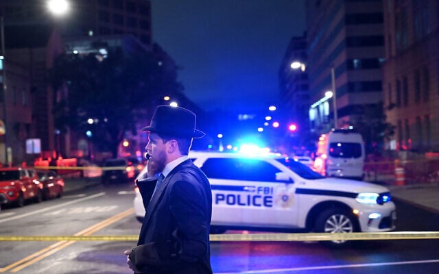 A Jewish man, standing behind US police tape, talks on his cellphone outside the Capital Jewish Museum following a shooting that left two people dead, in Washington, DC, on May 21, 2025. (Alex WROBLEWSKI / AFP)